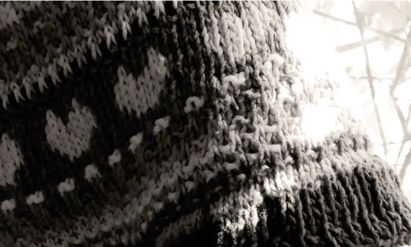 Sleeve of a knitted sweater with a heart on it.