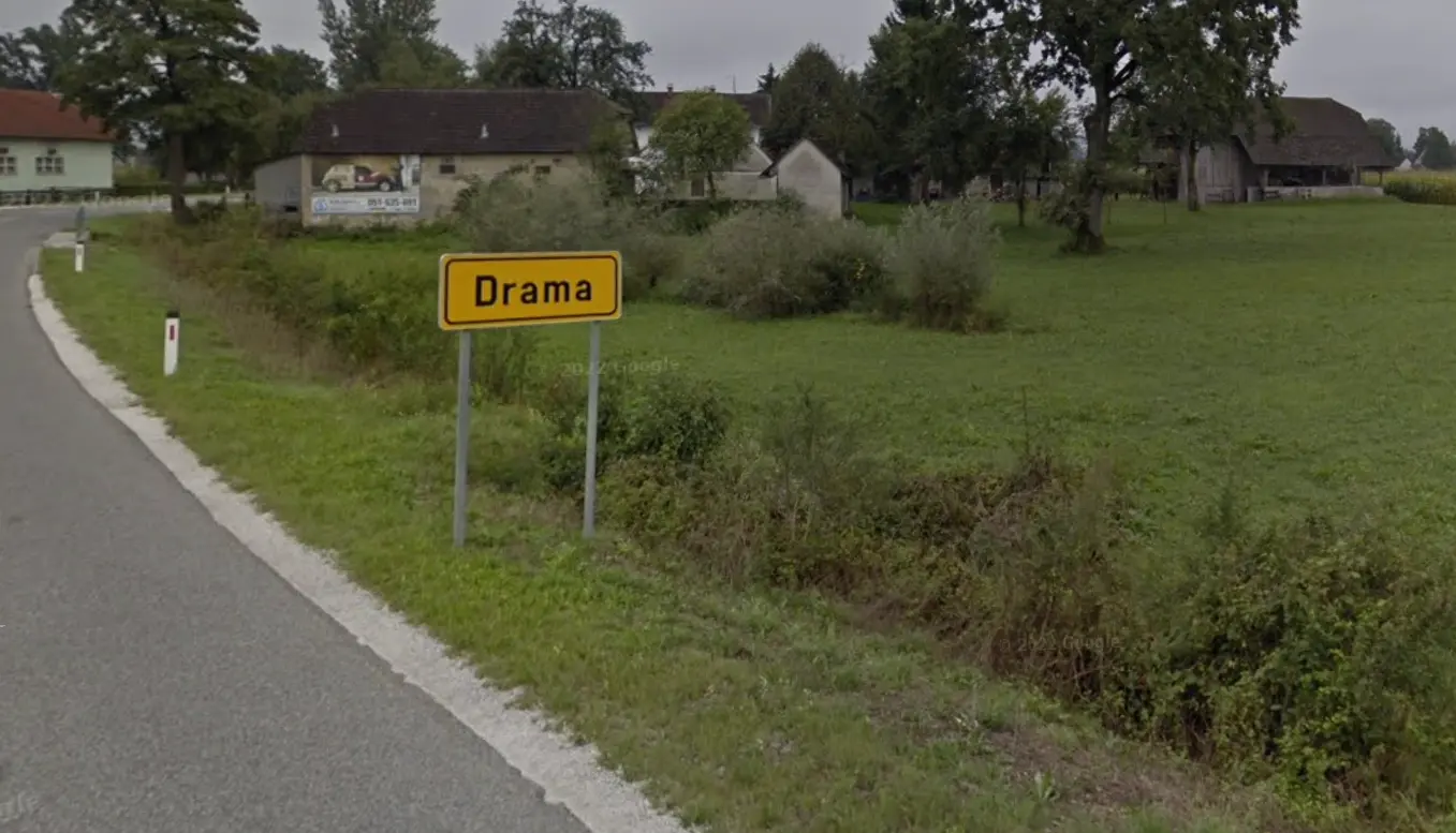 Photo of a field next to a roadway with a yellow sign reading