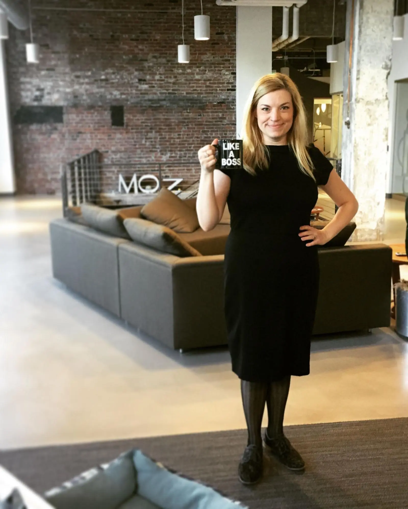 Sarah Bird posing in the Moz offices with her 'Like a Boss' mug.