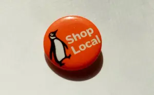 Shop local badge with an image of a penguin on it.
